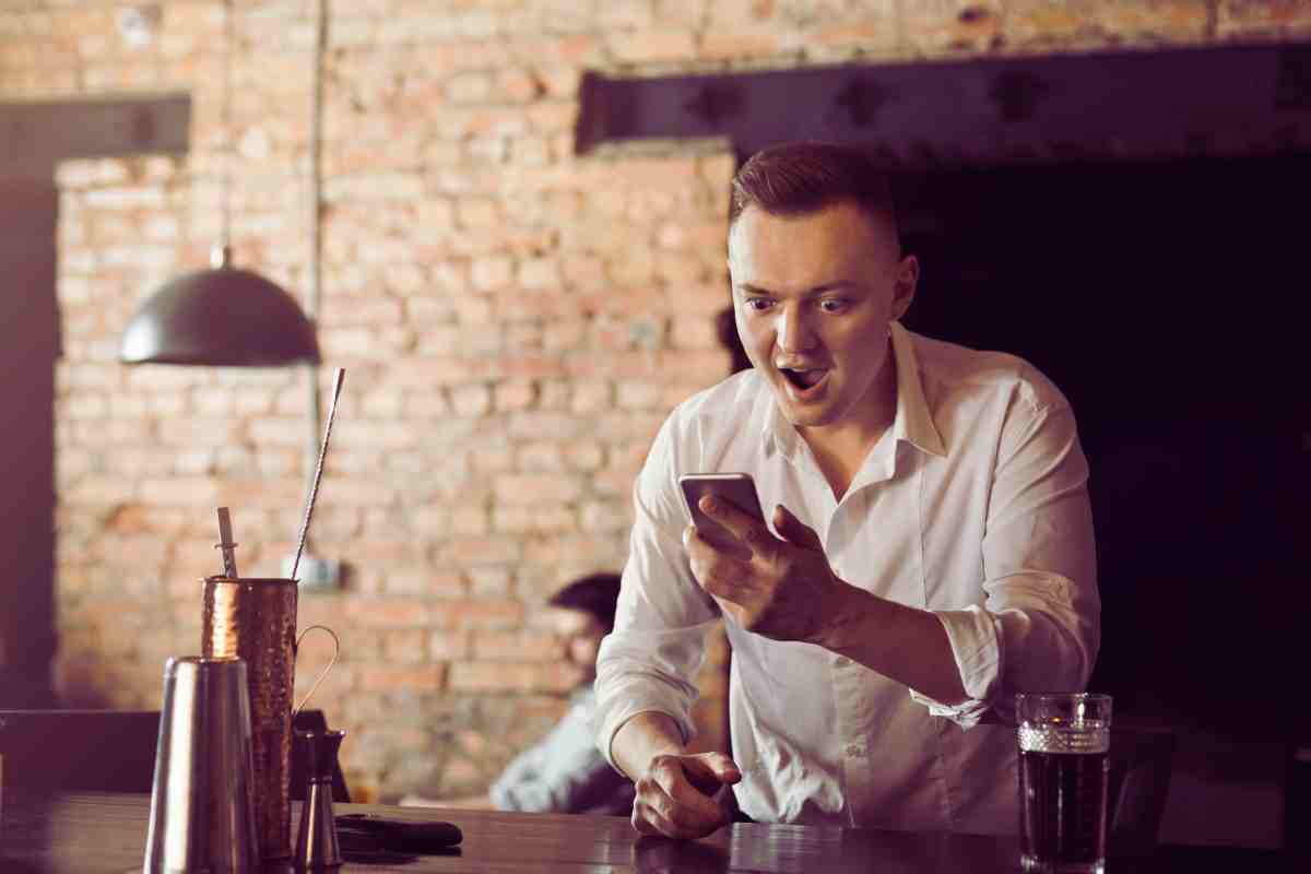 persona che guarda il cellulare ed esulta
